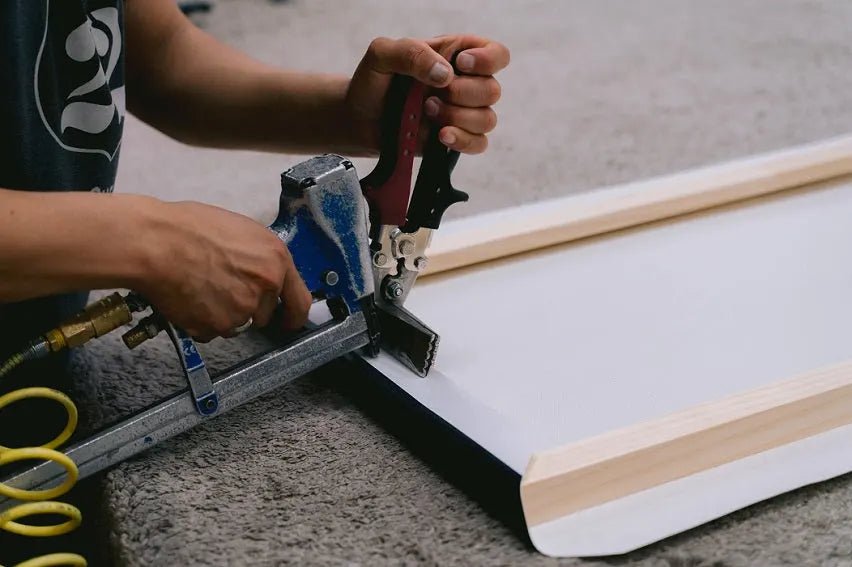 Stapling stretched canvas onto solid wood stretcher bars in The Dope Art shop